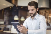 Young businessman using tablet in a cafe — Stock Photo