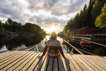 Finland, Kajaani, Man sitting on jetty, watching sunset, rear view — Stock Photo
