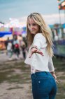 Sorridente giovane donna divertirsi nel parco divertimenti, guardando la fotocamera e dando mano — Foto stock