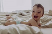 Happy baby, lying on bed, laughing — Stock Photo