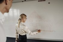 Empresária desenho casa no quadro branco — Fotografia de Stock