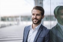 Porträt eines lächelnden jungen Geschäftsmannes an Glasfassade — Stockfoto