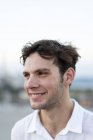 Porträt eines lächelnden jungen Mannes mit zerzausten Haaren im Freien — Stockfoto