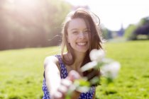 Retrato de una joven sonriente en el parque sosteniendo flores - foto de stock