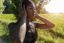 Young athlete in nature, listening music with headphones, preparing for training — Stock Photo
