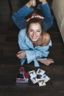 Portrait of happy young woman lying on floor with instant photos — Stock Photo