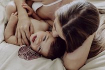 Mamma coccole con bambino figlio sul letto — Foto stock