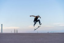 Молодий чоловік робить трюк на скейтборді на провулку в сутінках — стокове фото