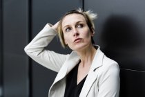 Portrait of pensive businesswoman looking up against black wall — Stock Photo