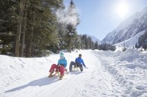 Couple sledding in snow-covered landscape — Stock Photo