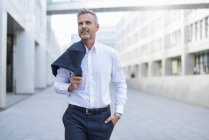 Portrait of businessman walking at courtyard of modern office building — Stock Photo
