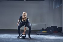 Mujer haciendo ejercicio con kettlebell en el gimnasio - foto de stock