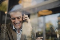 Homme d'affaires mature assis dans un café, parlant au téléphone — Photo de stock