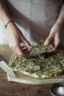 Mujer joven adornando garbanzos caseros y pastel de hierbas - foto de stock