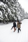 Италия, Модена, Чимоне, пара с лыжниками и сноубордистами, гуляющими по зимнему лесу — стоковое фото