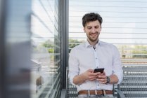 Lächelnder Geschäftsmann auf Bahnsteig mit Handy — Stockfoto