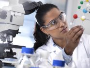 Biotechnologie Research, chercheuse scientifique examinant une formule chimique à l'aide d'un modèle moléculaire à boule et à bâton en laboratoire — Photo de stock