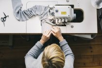 Vista superior de la modista mujer utilizando la máquina de coser en el estudio, fábrica de tela - foto de stock