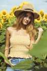 Retrato de mujer joven con sombrero de paja en un campo de girasoles - foto de stock