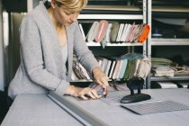 Créatrice de mode femme en studio travaillant avec du tissu gris à table — Photo de stock