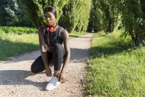 Junge Athletin kauert auf Schotterpiste und bindet Schuhe — Stockfoto