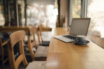 Ordenador portátil con pantalla en blanco en la cafetería - foto de stock