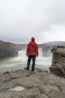 Islandia, norte de Islandia, joven mirando a la cascada - foto de stock