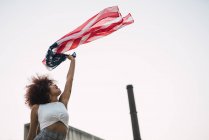 Young woman swinging American flag against clear sky — Stock Photo