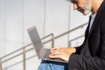 Businessman sitting outdoors using laptop — Stock Photo