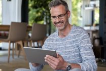 Smiling mature man at home using a tablet — Stock Photo