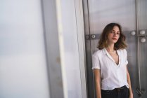 Portrait of a serious young woman posing in front of metal door — Stock Photo