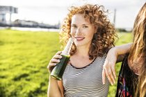 Deutschland, köln, porträt einer rothaarigen jungen frau beim trinken — Stockfoto
