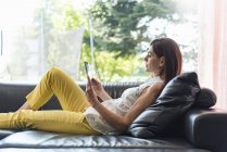 Frau liegt mit Tablet zu Hause auf Couch — Stockfoto