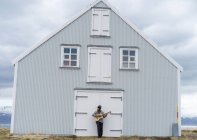 Islândia, jovem tocando guitarra, casa de madeira — Fotografia de Stock