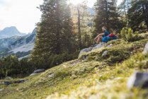 Austria, Tirol, Senderista tomando un descanso, sentado en una roca - foto de stock