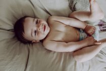 Счастливый ребенок, лежащий на кровати и смеющийся — стоковое фото