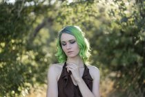 Portrait of young woman with dyed green hair and eyebrows in nature — Stock Photo