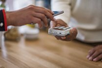 Крупним планом клієнт платить без каси зі смартфоном за лічильником магазину — стокове фото