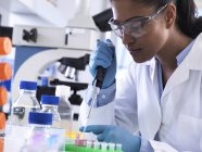 Recherche génétique, femme scientifique pipettant de l'ADN ou un échantillon chimique dans un flacon eppendorf, analyse en laboratoire — Photo de stock