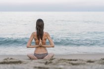 Bella donna sulla spiaggia che pratica yoga — Foto stock