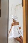 Жінка загорнута в рушник і сидить на краю ванни. — Stock Photo