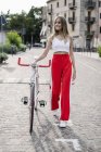 Улыбающаяся девочка-подросток толкает велосипед в городе — стоковое фото