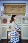 Waitress walking past drinks menu in a cafe — Stock Photo