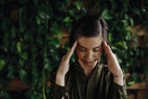 Focused young woman at wall with climbing plants — Stock Photo