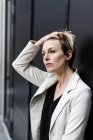 Portrait of pensive businesswoman leaning on black wall — Stock Photo