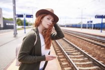 Retrato de mujer pelirroja con sombrero de pie en la plataforma - foto de stock