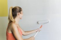 Jovem parede de pintura mulher na nova casa — Fotografia de Stock