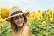 Mujer joven con sombrero de paja sonriendo en un campo de girasoles - foto de stock