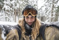 Портрет улыбающейся молодой женщины в лыжной одежде в зимнем лесу — стоковое фото