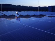 Arbeiter mit Messgerät überprüft Solaranlage am Abend — Stockfoto
